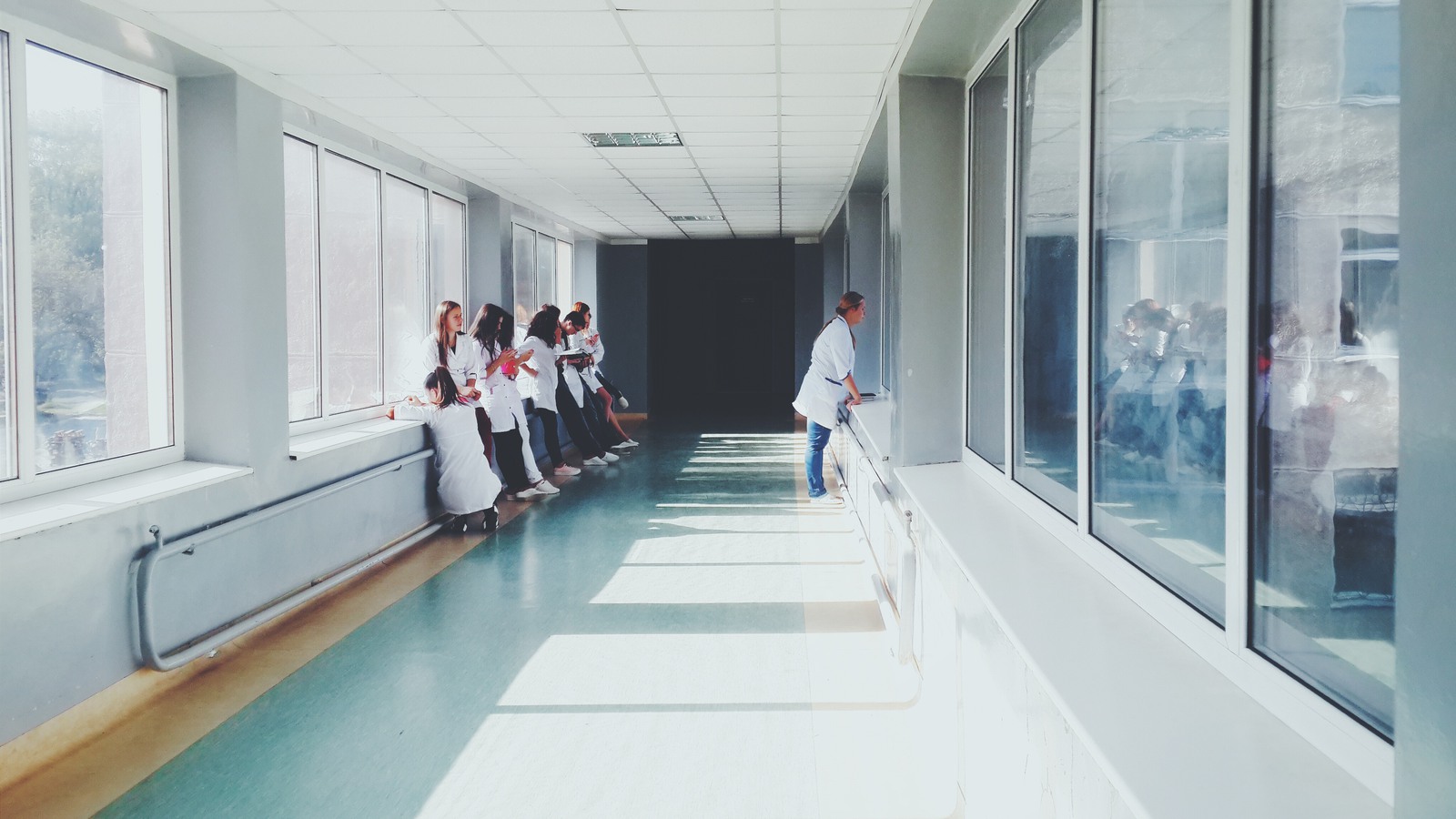 lång sjukhuskorridor med vårdpersonal som pratar längs sidorna