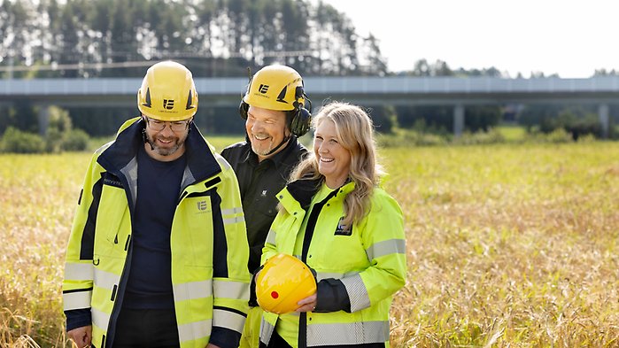 Tre personer i gula varselkläder och gula hjälmar som jobbar på Umeå Energi